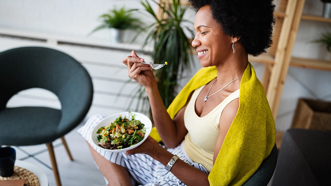 Farbige Frau isst gesundes Essen und ist sichtlich erfreut