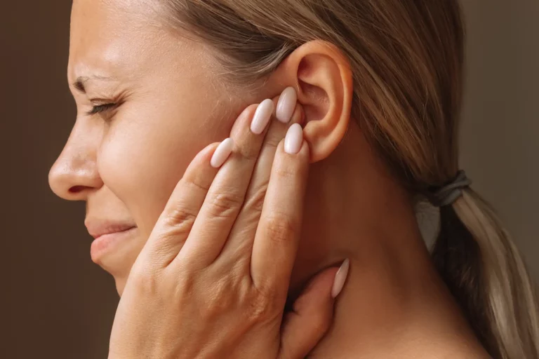 Eine Frau greift sich auf ihr anscheinend schmerzendes Ohr